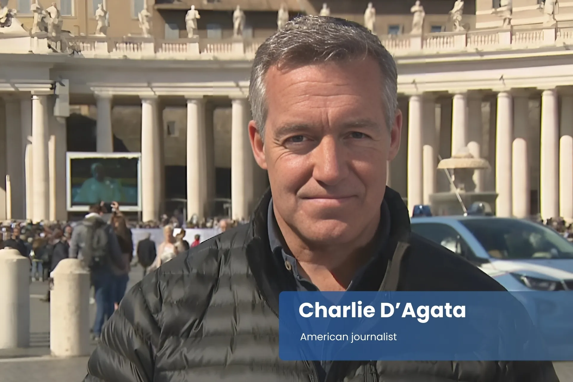 Charlie D’Agata black jacket, in front of building